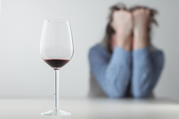Glass with alcohol on blurred view of a lonely and desperate drunk man