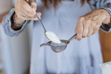 Woman putting sugar into sieve