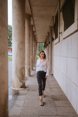 A beautiful young caucasian girl in front of a white building with pillars