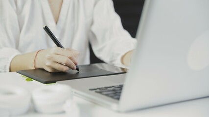 Close up of designer working at a laptop with a graphics tablet.