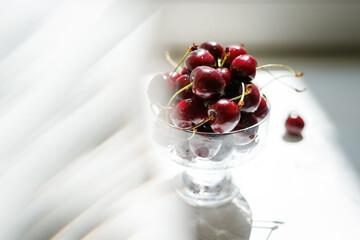 sweet cherries in a glass bowl on a bright white surface