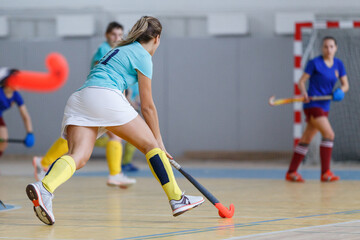 Young female indoor hockey player in attack