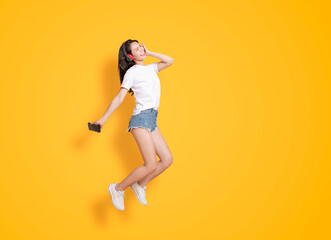 Fototapeta na wymiar young woman jumping while listening to music on headphones
