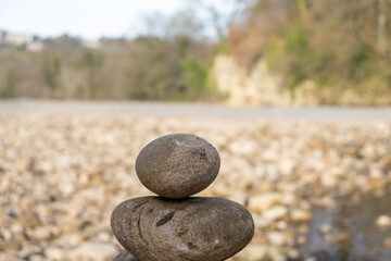 The top of a stack of balancing stones with a rocky beach in the background.