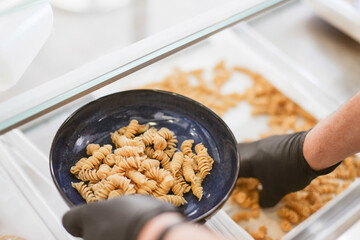 A process of cooking pasta, putting fresh made pasta on a plate, hands in black gloves