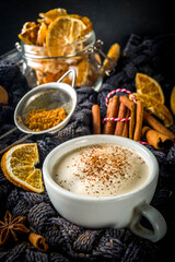 Autumn sweet hot drink, Chai Buttered Rum, Pumpkin Pie or Pumpkin Spice Coffee Latte. Cozy autumn background with traditional latte cup, spices and old sweater, on rustic wooden background