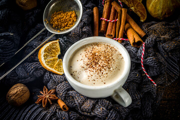 Autumn sweet hot drink, Chai Buttered Rum, Pumpkin Pie or Pumpkin Spice Coffee Latte. Cozy autumn background with traditional latte cup, spices and old sweater, on rustic wooden background