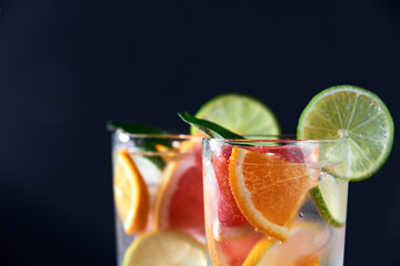 Infused water with grapefruit, orange, lemon, lime and ice on dark background