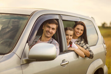 Cute girl with her mom and dad looking out of car windows on road trip. Family with child on auto journey in countryside