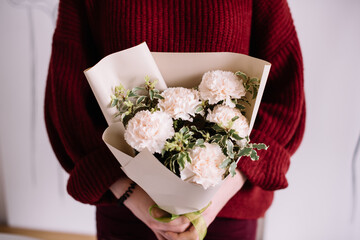 Very nice young woman holding beautiful blossoming mono bouquet of fresh pink carnations on the...
