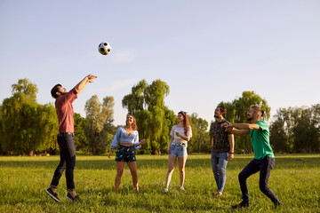 Happy friends playing volleyball game in countryside on summer day. Group of students having fun...