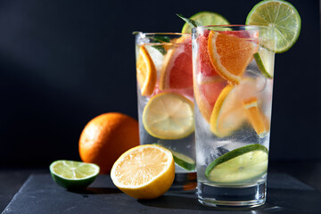 Infused water with grapefruit, orange, lemon, lime and ice on dark background