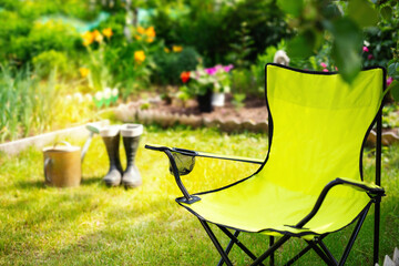 Garden at summer day,  chair, watering can and boots