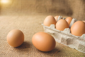 Front view on fresh organic chicken eggs from local farmer market in paper packaging box standing on the table, in sunny day. Healthy organic food concept. Copyspace for your text or presentation