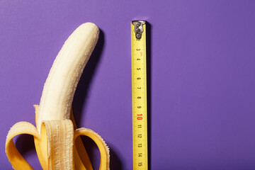 A banana is measured using a yellow ruler on a purple background. Adult material