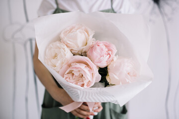 Very nice young woman holding big and beautiful mono bouquet of fresh pink peonies, cropped photo, bouquet close up