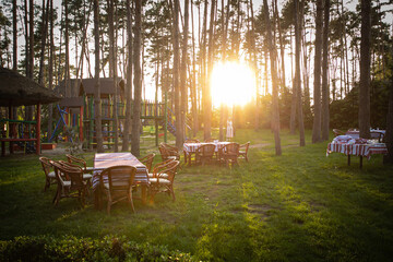 Tables are served on a glade among pines. The summer sun sets  © Борис Яценко