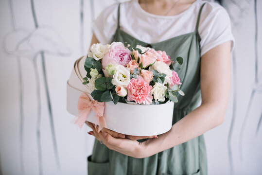 Very nice young woman holding beautiful flower bouquet of fresh peony, roses, eustoma, carnations in tender pink  colors, inside a baby’s carriage bed, cropped photo, bouquet close up