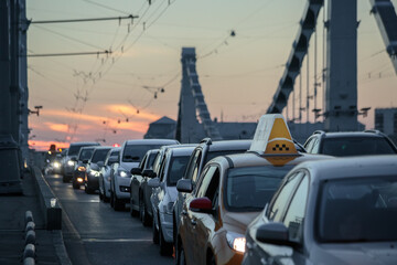 Cars with their headlights on stand in traffic on the Krymsky bridge in Moscow during sunset