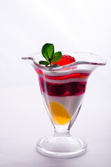 milk fruit dessert souffle mousse with pieces of jelly in a beautiful glass on a leg on a white background
colored jelly