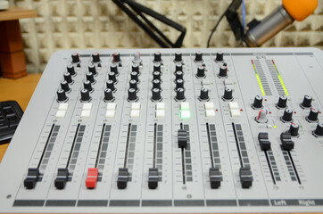 Close up of professional multitrack mixing console in production studio. Radio station. Potentiometers and VU meter lights. Equipment in studio. Recording and broadcasting program. Live show. On air.
