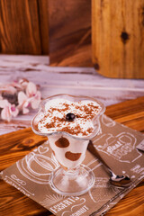 coffee chocolate dessert souffle mousse with white cream poured with chocolate in a beautiful glass on a leg against the background of pieces of chocolate and mint on a gray napkin for serving 