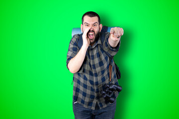 Young traveler man pointing and looking at copy space. Handsome young businessman isolated on green background