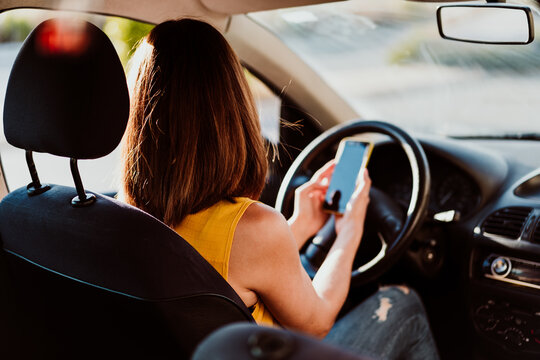 Young Woman In A Car Using Mobile Phone, Wearing Protective Mask. Summer Season. Prevention Corona Virus Concept