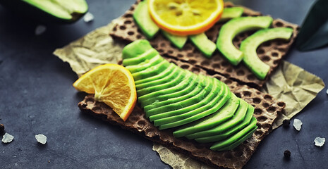 Avocado cooking recipes. Ripe green avocado on a wooden cutting board for serving.