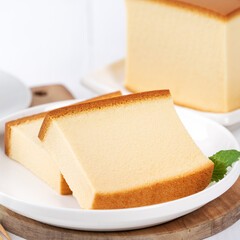 Castella (kasutera) - Beautiful delicious Japanese sliced sponge cake food on white plate over rustic white wooden table, close up, copy space design concept.