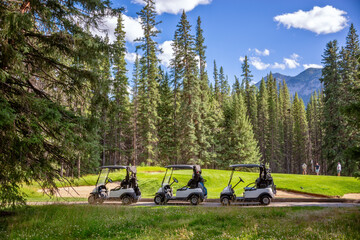 Row of empty electric carts on the side of the golf course, in Banff, Alberta, Canada - obrazy, fototapety, plakaty