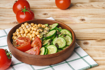 Clay plate of chickpeas and cut cucumbers and tomatoes. Healthy eating
