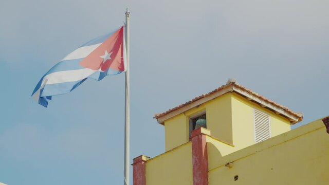 A cuban flag at the top of a yellow building in the city of Trinidad, Cuba