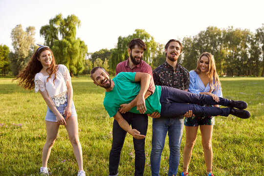 Friends Having Fun In Wilderness During Their Summer Trip In Park. Group Of People Being Silly Outdoors