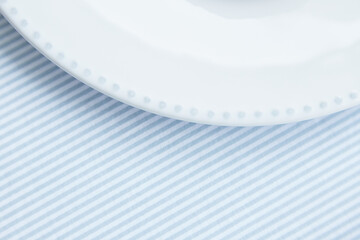 Empty plate edge with dots ornament on a table with blue striped tablecloth. Space for text, copy space. Minimalistic.