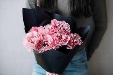 Very nice young woman holding beautiful blossoming mono bouquet of fresh pink japanese ranunculus...