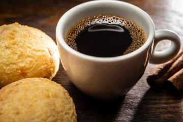 Xícara de café com pães de queijo e canela.
