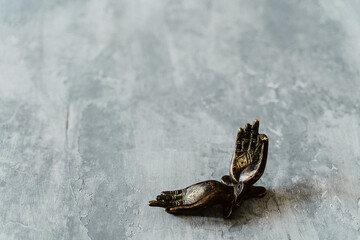 metal door handles in the shape of hands folded in mudra, shot on a textured gray background, close-up, separate object, yoga theme, bronze shade, Indian motif