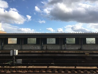 Empty elevated subway platform in New York City. Vacant overground subway station on a bright day with blue skies. Empty train station in NYC.