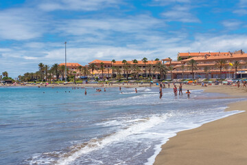 View of the tropical beach situated between Los Cristianos and Las Americas populated with few residents enjoying the weather, at Playa de las Vistas, Arona, Tenerife, Canary Islands, Spain
