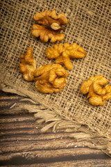 Peeled walnuts in bulk on a wooden table covered with rough-textured burlap. Healthy diet. Fitness diet. Close up.