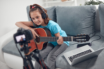 Fototapeta na wymiar Child guitarist making video lessons and tutorials for internet vlog website classes.