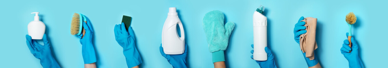 Hands in gloves holding detergent bottles on blue background. Banner with copy space. Chemical...