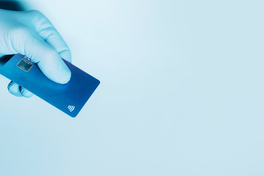 Contactless payment concept, copy space. Hand in protective gloves holding credit card with contactless symbol, electronic chip. Online shopping, online banking. Payment by plastic cards.