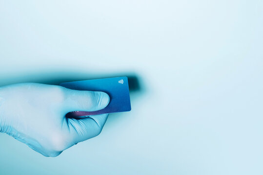 Contactless payment concept, copy space. Hand in protective gloves holding credit card with contactless symbol, electronic chip. Online shopping, online banking. Payment by plastic cards.
