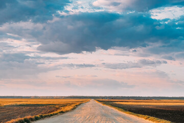 Fototapeta na wymiar Evening Sky Above Rural Landscape With Country Road Through Spring Soil Field Pathway, Way, Open Road In Agricultural Landscape