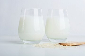 Two glass of vegatarian rice milk and rice grains on white background. Non dairy alternative milk. Concept of proper nutrition and healthy eating. Organic food. Copy space for text, selective focus