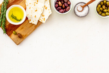 Fototapeta na wymiar Mediterranean olives near bread on cutting board top view copy space