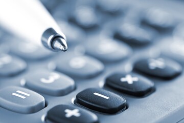 Pocket calculator with pen on financial analysis sheet background - tax, finance or accounting concept