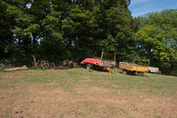 Fototapeta na wymiar Group of Old farm Machinery and Agricultural Trailers Parked on Top of a Hill in a Field on a Farm in Rural Devon, England, UK